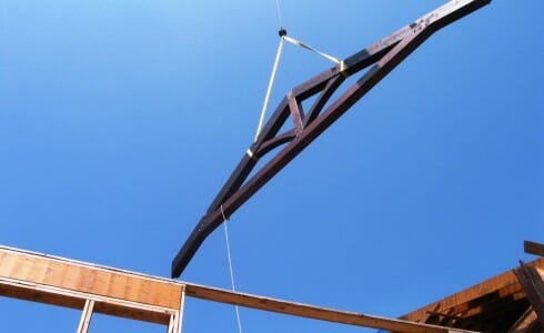 The king post truss being lowered into place by a crane