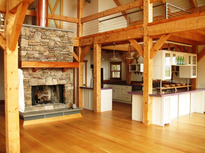 Hand hewn beams with a stone fireplace in a great room and kitchen