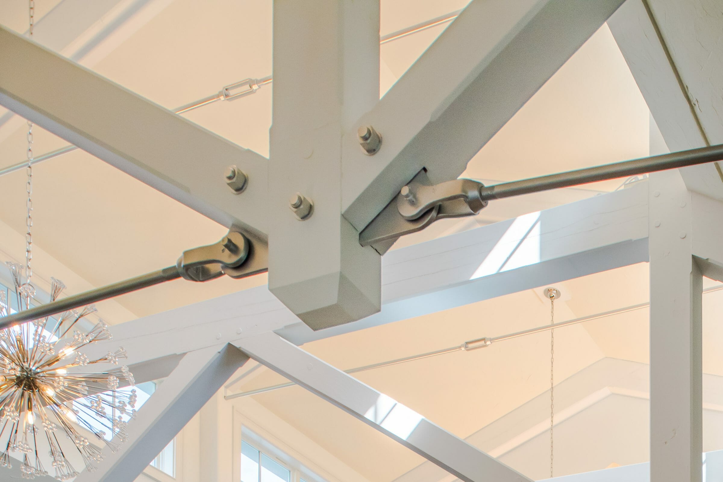 Steel tie bar and steel plate joinery details on a white timber truss in the Anya Restaurant in Thompson, CT.