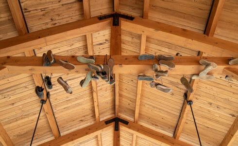 Sneakers Hanging from exposed wood beams in a timber frame pavilion.