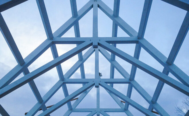 Scissor trusses with a dramatic pitch that have been stained white for a private chapel/pool building