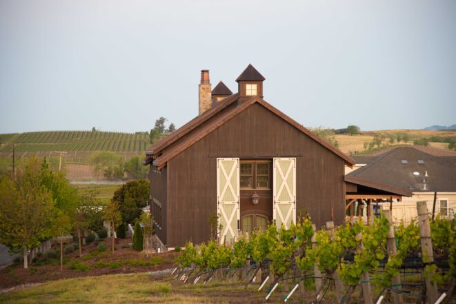 Exterior of the barn nestled between rows of grape vines