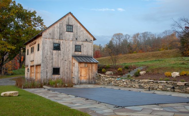 Timber Frame Barn next to a stone wall and swimming pool