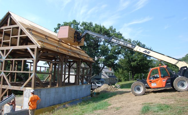 Roof sheathing being installed on a timber frame barn