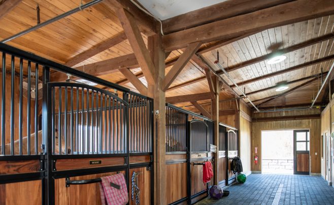 The stalls and aisle of a timber framed horse barn
