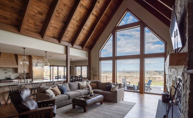 Post and beam home with a window wall and stone fireplace.