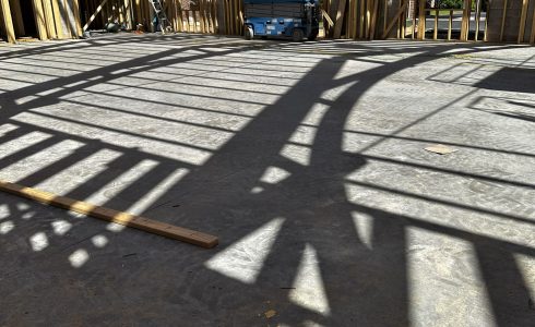 Shadows of a heavy timber arched truss being installed.